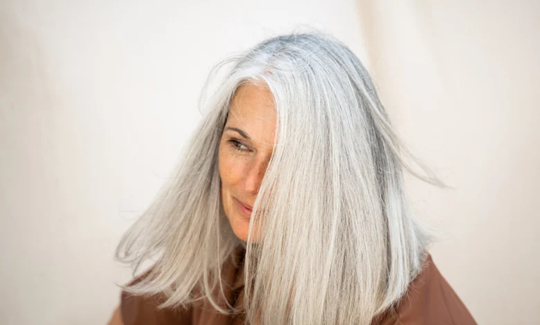 woman with medium gray hair and brown jacket
