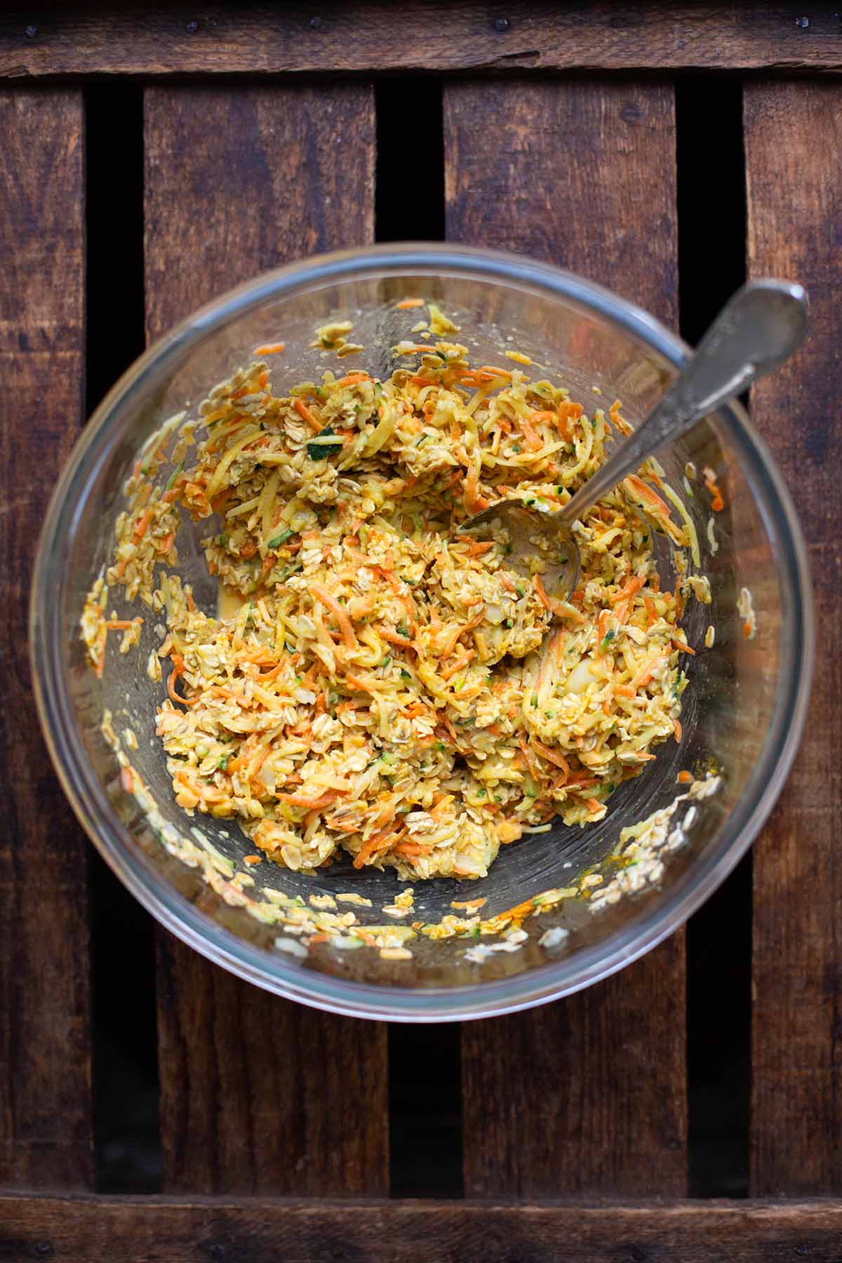 All mixed ingredients for the vegetable frequency in a glass bowl. With a silver spoon, the dough is ready for processing.