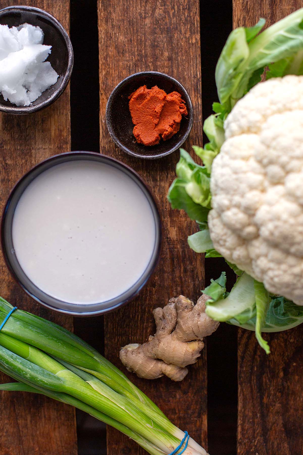Ingredients for the curry recipe divided into bowls. You can see: cauliflower, coconut milk, curry paste, ginger, spring onion and coconut oil.