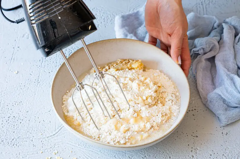 The dough for the banana bread without egg is mixed with the hand mixer in a bowl.