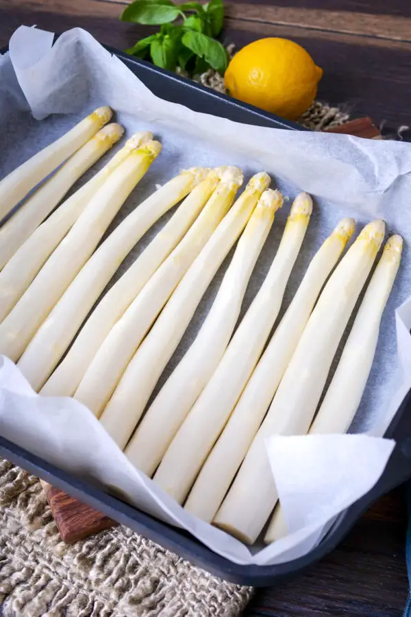 Prepared asparagus on baking paper on a baking sheet.