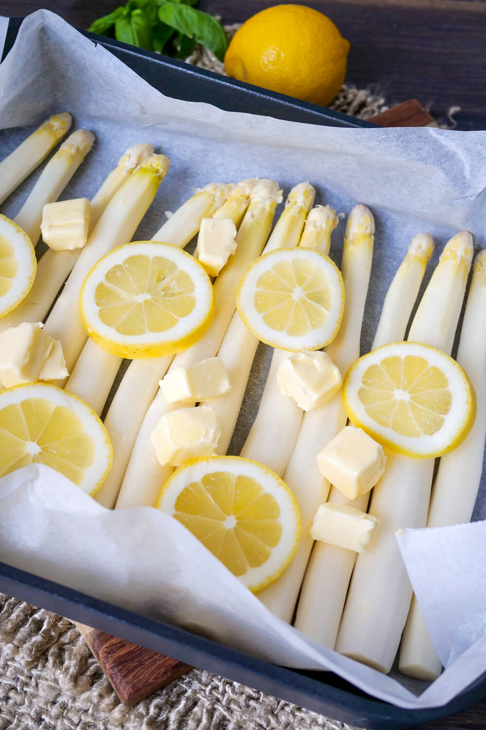 Prepared asparagus on baking paper with butter and lemon.