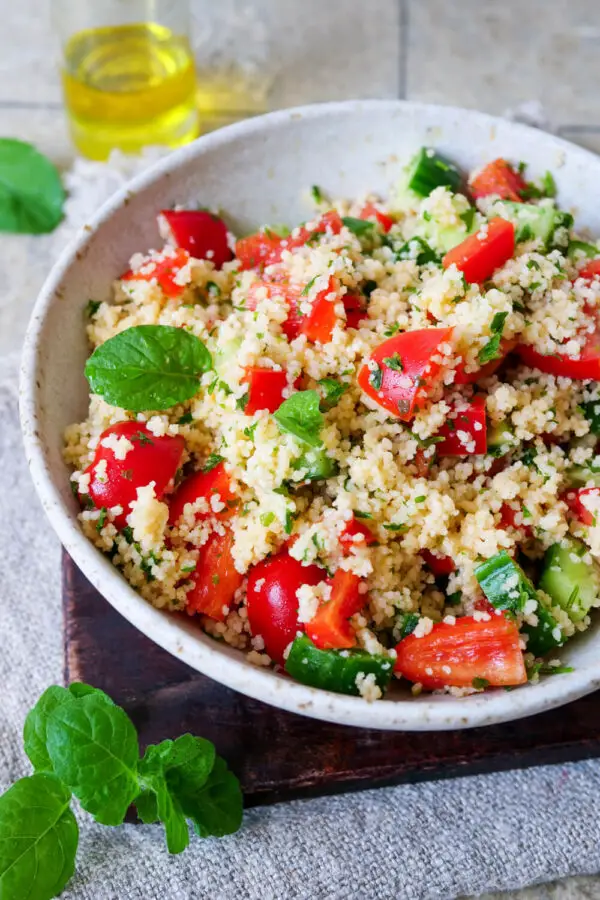 Couscous with peppers and cucumber arranged on a deep plate.