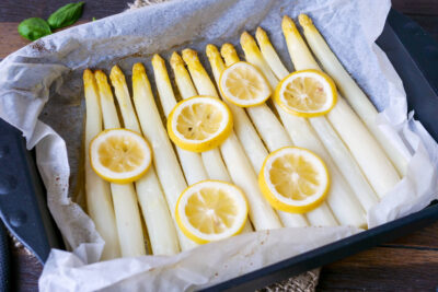 Asparagus cooked in the oven with lemon on a baking sheet.