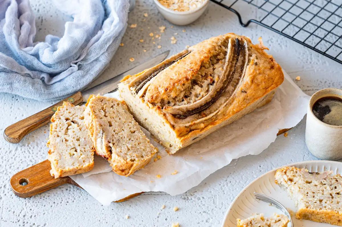 Banana bread without egg on a cutting board, two pieces have already been cut.