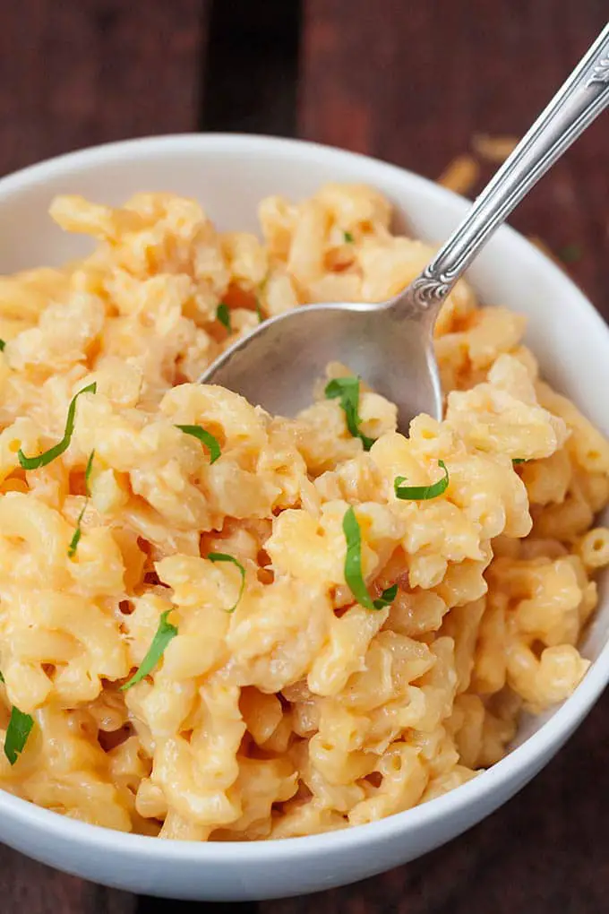 One pot mac and cheese. Perfect cheese and on the table in 15 minutes! So good - kochkarussell.com Finished Mac and Cheese in a white bowl with a silver spoon. The bowl stands on a dark wooden surface.