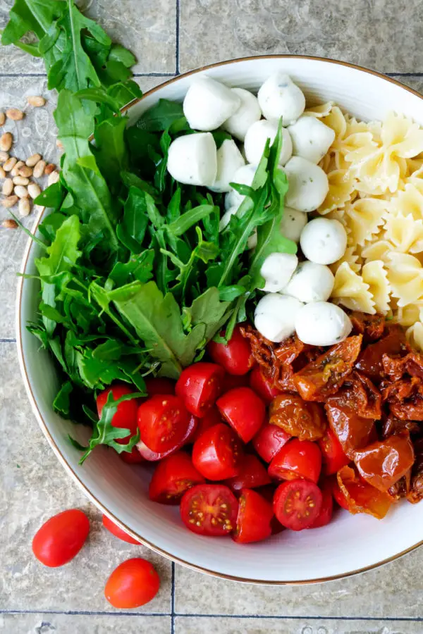 Rucola, tomatoes, mozzarella, dried tomatoes and noodles are the ingredients for the Italian pasta salad