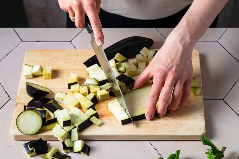 Cut the eggplant An eggplant is cut into cubes on a cutting board.