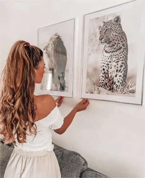 Young girl hangs two pictures with tigers and lions