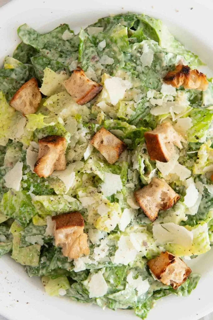 Classic Caesar Salad Recipe: Roman salad in a creamy dressing, garnished with large croutons, planed parmesan and black pepper.