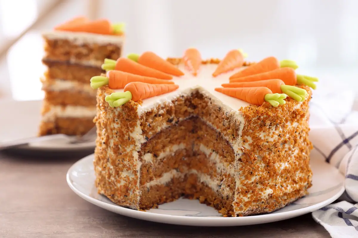 round carrot cake in layers and decorated with small carrots above 