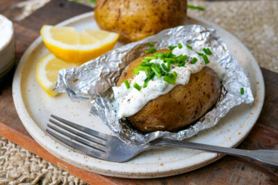 Foil potatoes with curd and fork on a plate.